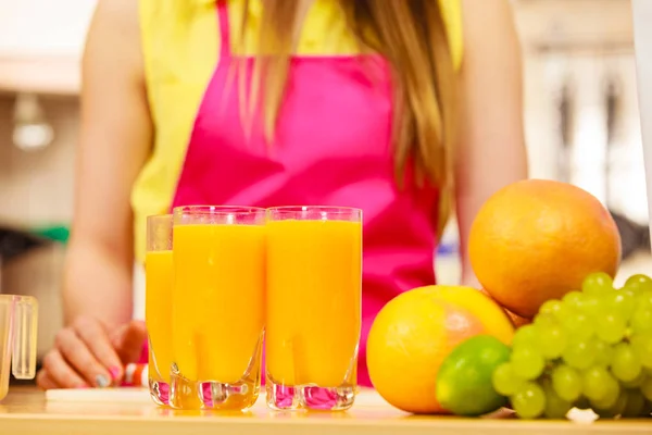 Mujer con frutas frescas y jugo en la cocina — Foto de Stock