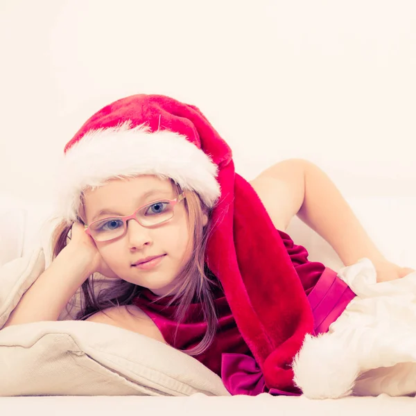 Christmas flicka i santa hatt liggande på soffan — Stockfoto