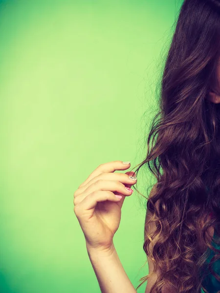 Mujer sostiene largo pelo castaño rizado — Foto de Stock