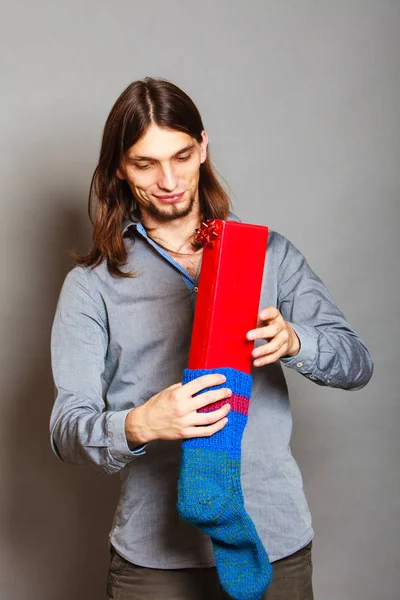 Хлопець кладе загорнутий подарунок у в'язану різдвяну шкарпетку — стокове фото