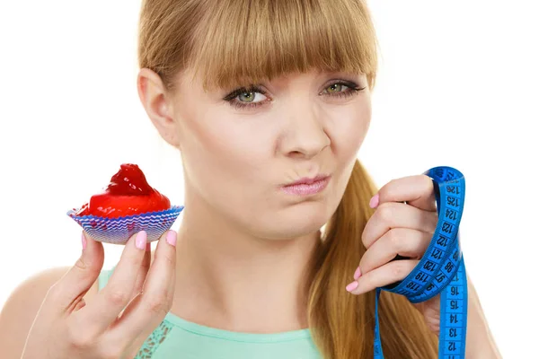 Frau hält Cupcake in der Hand und versucht der Versuchung zu widerstehen — Stockfoto