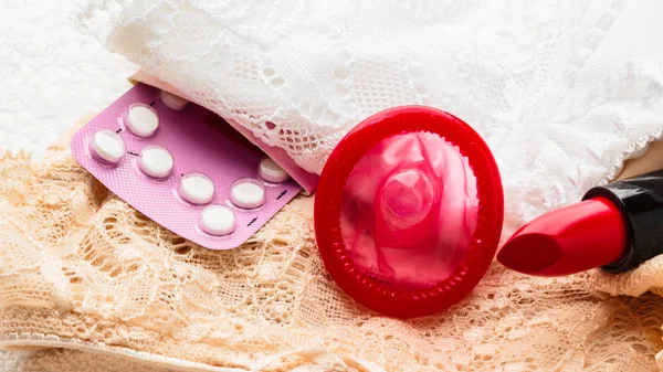 Píldoras condón y lápiz labial en ropa interior de encaje —  Fotos de Stock