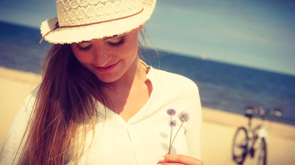 Usměvavá dívka s květinou na pláži — Stock fotografie