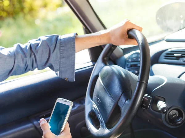 Man met behulp van zijn telefoon tijdens het rijden auto. — Stockfoto
