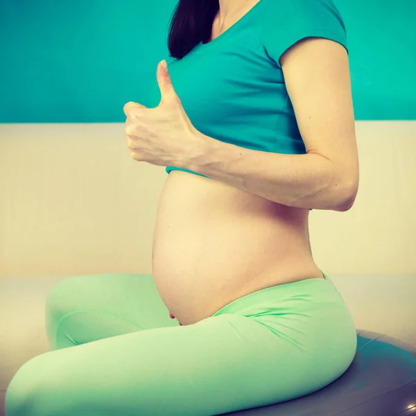 Femeie gravidă așezat pe mingea de potrivire, degetul mare în sus gest — Fotografie, imagine de stoc