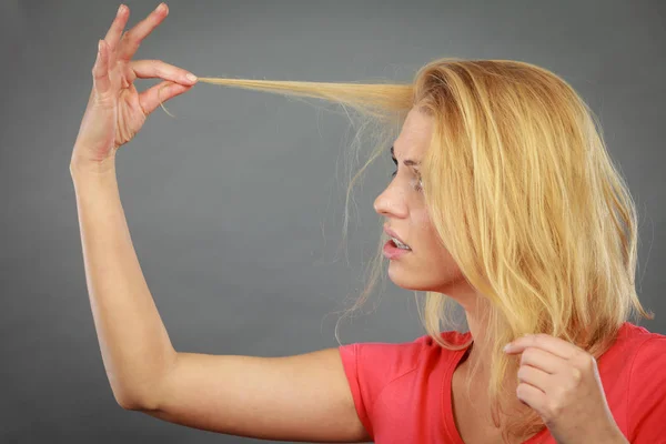 Traurige Frau blickt auf beschädigte Haarspitzen — Stockfoto