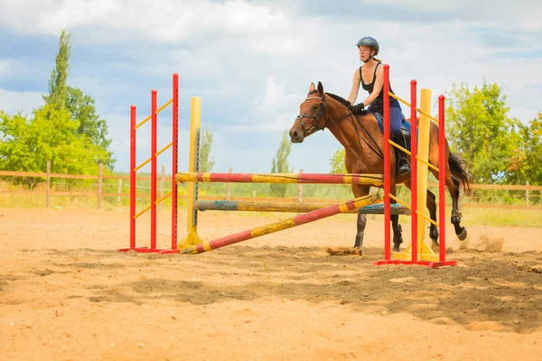 Jockey joven chica haciendo caballo saltar a través de obstáculo — Foto de Stock