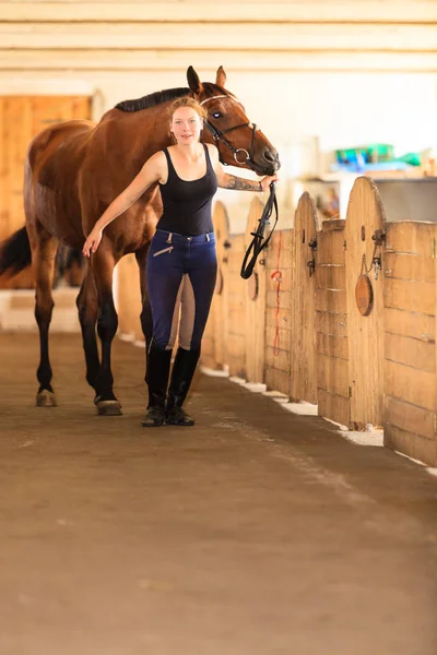 Jóquei menina acariciando cavalo marrom — Fotografia de Stock