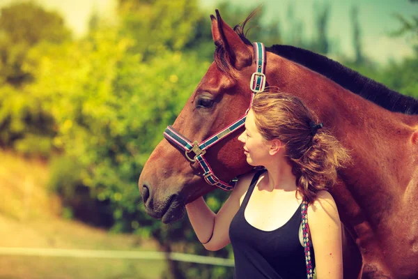 Jóquei menina petting e abraçando cavalo marrom — Fotografia de Stock