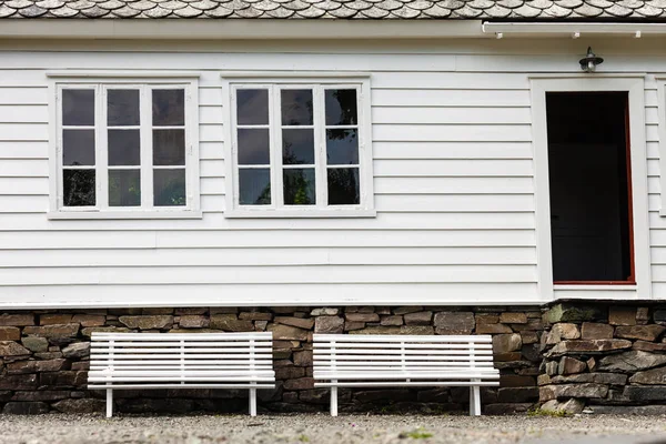 Banc symétrique à deux blancs devant la maison traditionnelle . — Photo