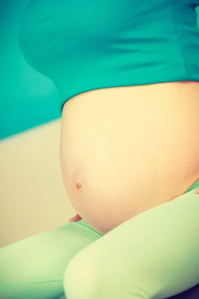 Femme enceinte assise sur le canapé, montrant son ventre — Photo