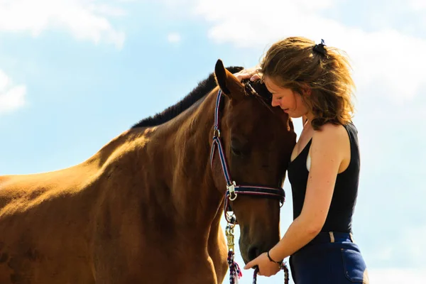 Jockey young girl kissing and hugging brown horse — Stock Photo, Image