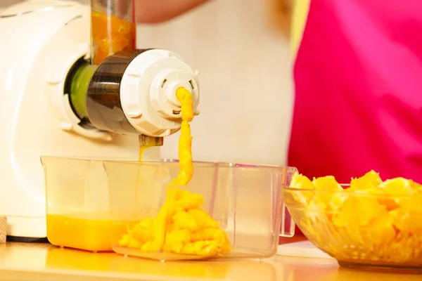 Производство апельсинового сока в соковыжималке на кухне — стоковое фото