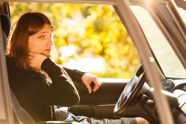Znudzony młody człowiek z długimi włosami, prowadzenie samochodu — Zdjęcie stockowe