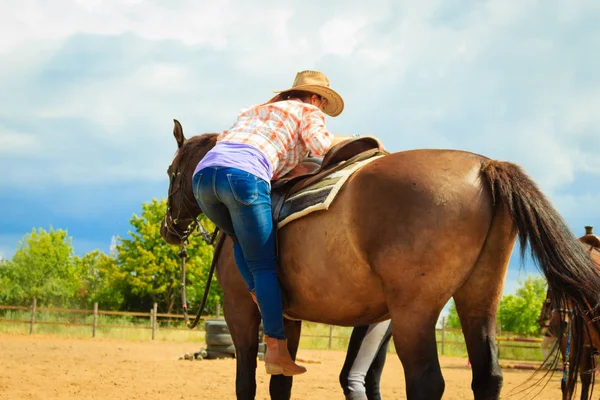 Cowgirl klaar paard voor rit op platteland — Stockfoto