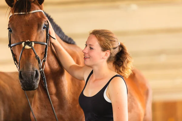 Jockey young girl petting and hugging brown horse — Stock Photo, Image