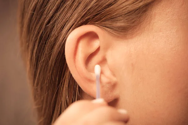 Женщина чистит уши ватными тампонами крупным планом — стоковое фото