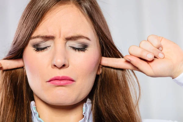 Stressad kvinna med slutna ögon sticka fingrarna i öronen, — Stockfoto