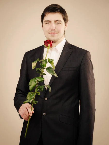 Elegante giovane uomo con rosa rossa . — Foto Stock