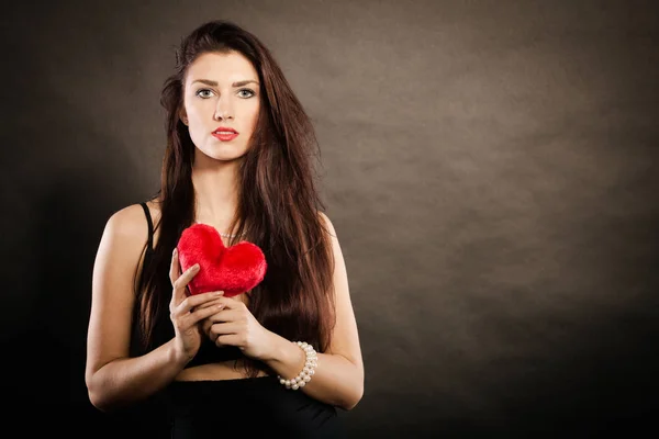 Hermosa mujer sostiene el corazón rojo en negro —  Fotos de Stock