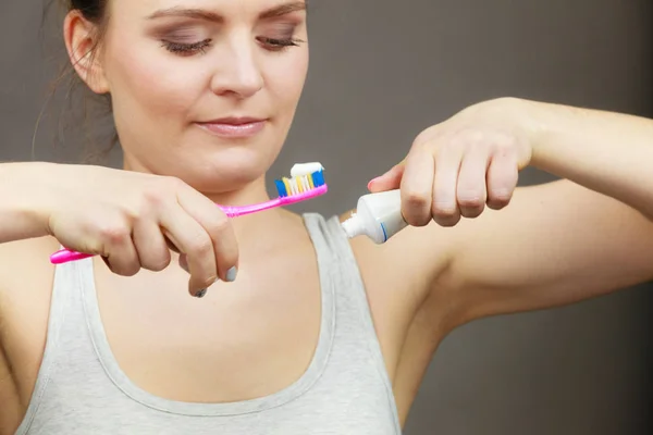 Kvinnan håller tandborste och utsläppande tandkräm på det — Stockfoto