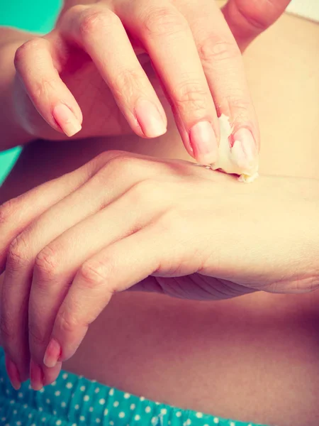 Женщина кладет белый крем на руку — стоковое фото
