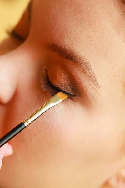 Fechar a mulher ficando maquiagem, sombra de olhos — Fotografia de Stock