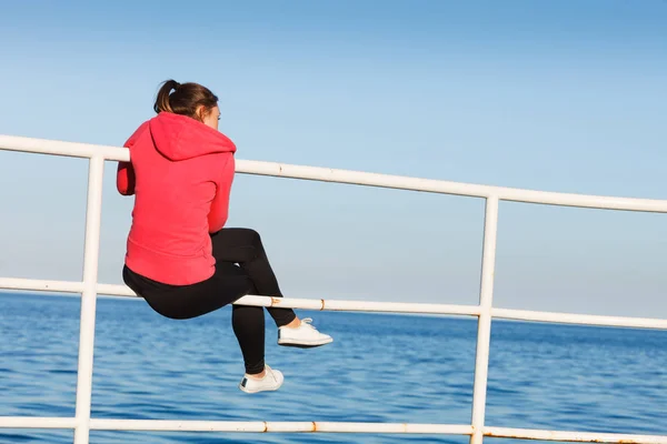 Frau sitzt auf Seebrücke und blickt auf Horizont — Stockfoto
