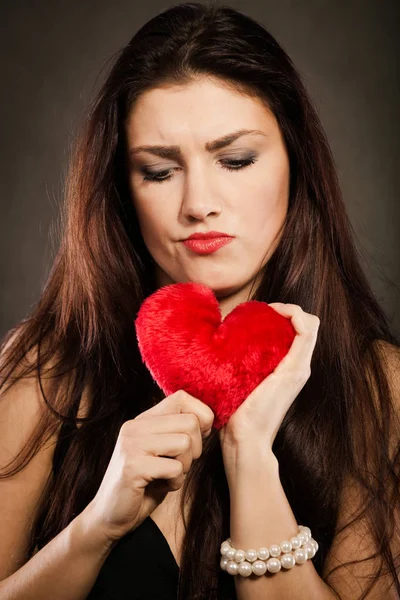 Sad lovely woman holds red heart on black — Stock Photo, Image