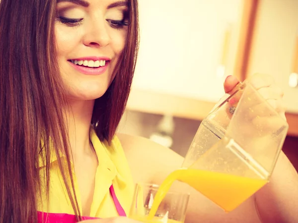 Woman make orange juice in juicer machine pouring drink in glass — Stock Photo, Image