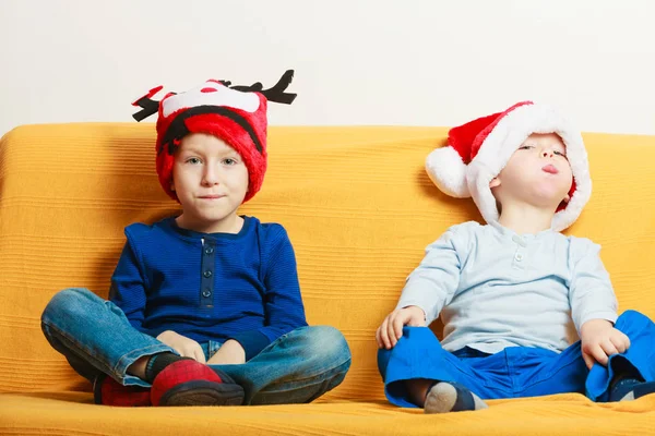 Dos chicos en el sofá con sombreros de Navidad — Foto de Stock