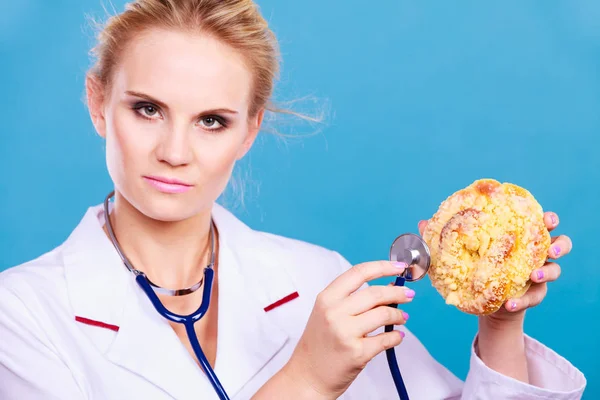 Diëtist onderzoeken zoete roll broodje met stethoscoop — Stockfoto