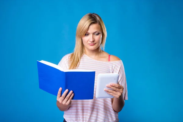 Femme blonde au choix entre livre et tablette — Photo