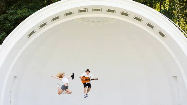 Мужчина с гитарой и женщина прыгает — стоковое фото