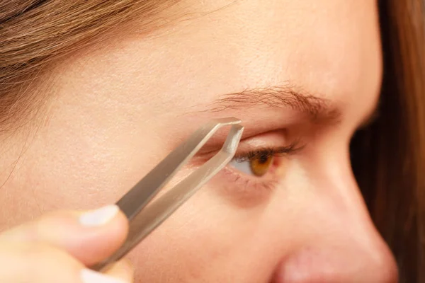 Frau pinselt Augenbrauen mit Pinzette ab — Stockfoto
