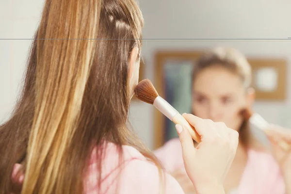 Mujer aplicando polvo bronceador con cepillo a su piel — Foto de Stock