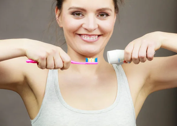 Mujer sosteniendo el cepillo de dientes y colocando pasta de dientes en él — Foto de Stock