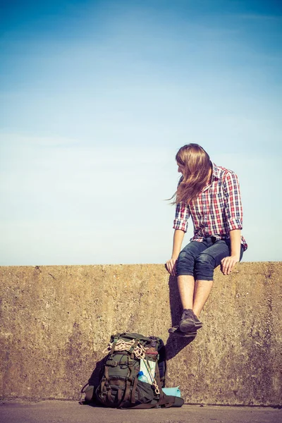 Man tourist backpacker sitting on grunge wall outdoor — Stock Photo, Image