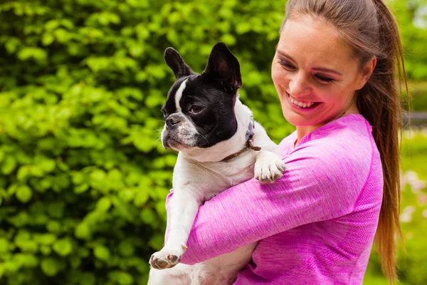 Leende kvinna som håller fransk bulldog utanför — Stockfoto