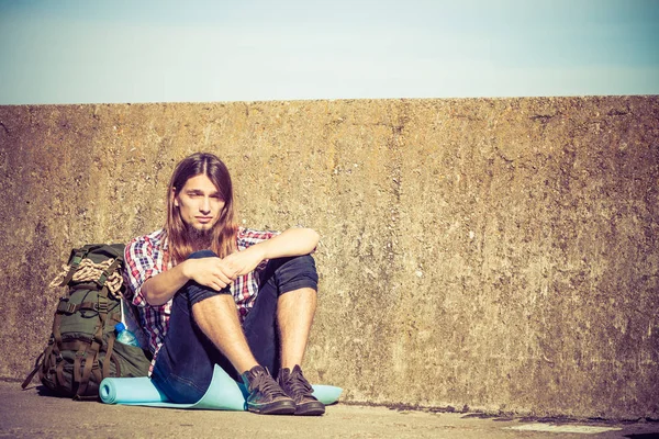 Açık Grunge duvar dibinde oturan adam turist backpacker — Stok fotoğraf