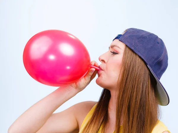 Genç kız üfleme kırmızı balon. — Stok fotoğraf