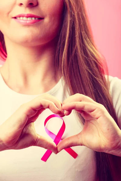 Breast cancer. Woman making heart shape on pink ribbon — Stock Photo, Image