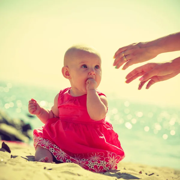 Babby siting on sand looking at hands — Stock Photo, Image