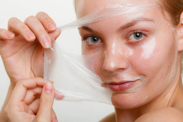 Frau entfernt Gesichtspeeling von Maske. — Stockfoto