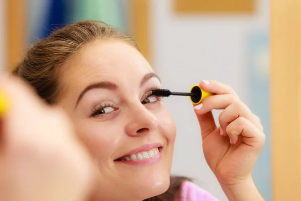 Woman applying black eye mascara to her eyelashes — Stock Photo, Image