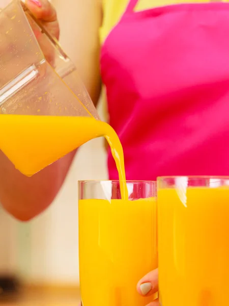 Mujer vertiendo jugo de naranja bebida en vidrio —  Fotos de Stock