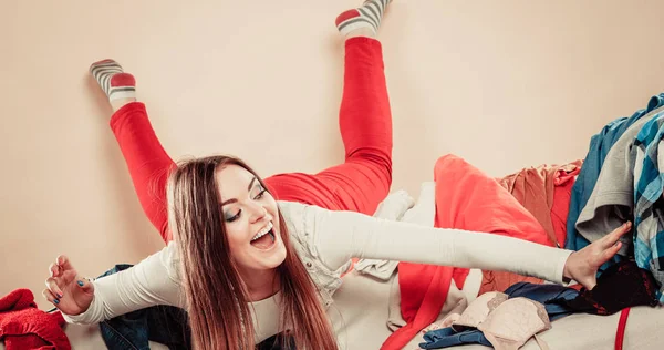 Woman lie on sofa full of clothes. — Stock Photo, Image