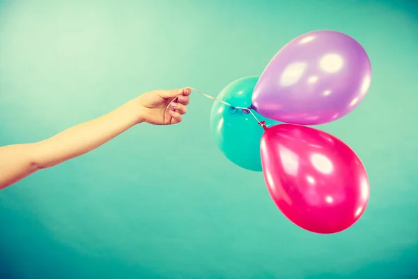 Female hand holding colorful balloons — Stock Photo, Image