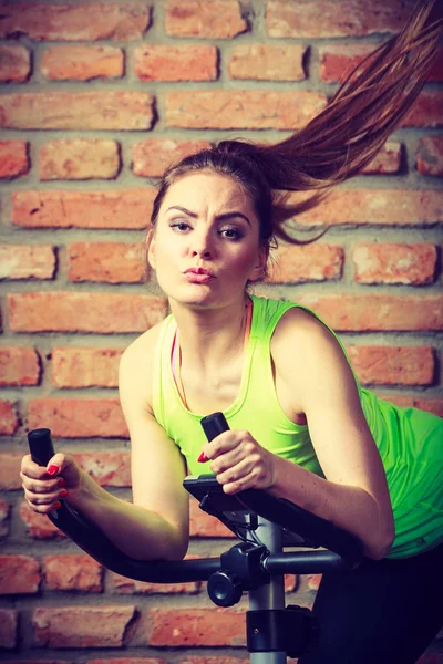 Mujer activa usando bicicleta estática en el gimnasio . — Foto de Stock
