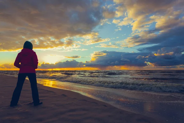 Mujer disfrutando de dramática puesta de sol en el mar — Foto de Stock
